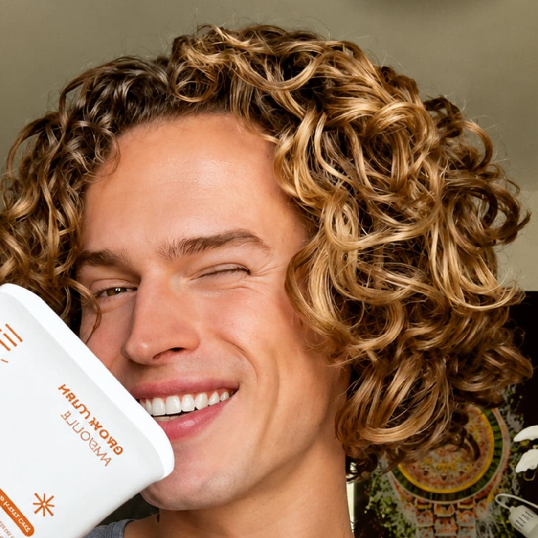 Someone with curly hair holding the scalp serum
